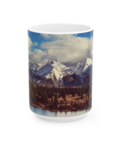 The scenic mountain landscape with snow-capped peaks, evergreen trees, and a cloudy blue sky.