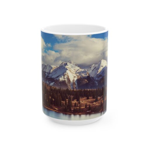 The scenic mountain landscape with snow-capped peaks, evergreen trees, and a cloudy blue sky.