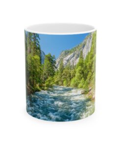 The Merced River rushing Yosemite Valley with lush green trees and rocky cliffs in the background.