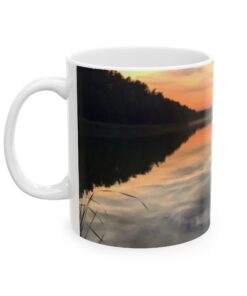 a coffee mug with a reflection of trees and a sunset