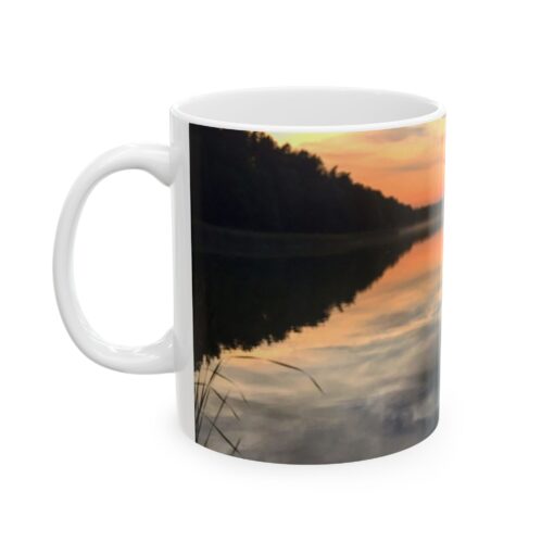 a coffee mug with a reflection of trees and a sunset