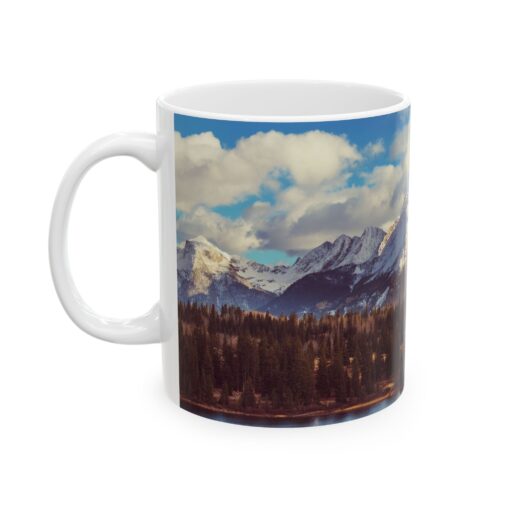 The scenic mountain landscape with snow-capped peaks, evergreen trees, and a cloudy blue sky.